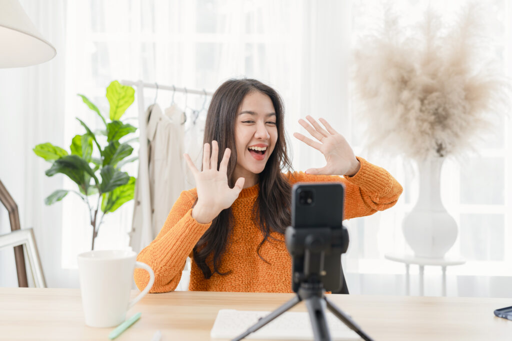 Female KOL Marketing smiling and waving at her phone camera